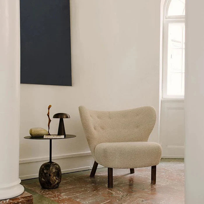 Beiger Sessel im skandinavischen Design neben modernem Beistelltisch, minimalistisches Wohnzimmer.