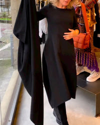 Frau in schwarzem Kleid im Modegeschäft, hält Stoff, moderne Damenmode, Herbstkollektion.