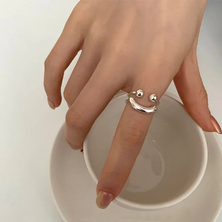 Silberner Smiley-Ring auf Hand, minimalistisches Design, Modeschmuck, Damenaccessoire.