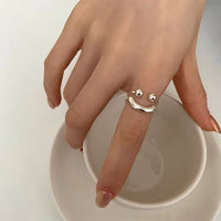 Silberner Smiley-Ring auf Hand, minimalistisches Design, Modeschmuck, Damenaccessoire.