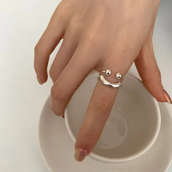 Silberner Smiley-Ring auf Hand, minimalistisches Design, Modeschmuck, Damenaccessoire.