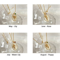 Goldene Halsketten mit Blumenanhängern für Mai, Juni, Juli, August auf Glasoberfläche.