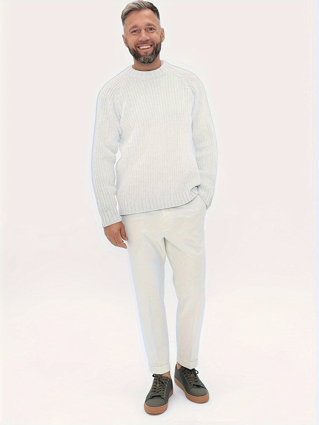 Mann in weißem Strickpullover und Hose, lächelnd, mit grünen Sneakers, modisch, lässiger Look.