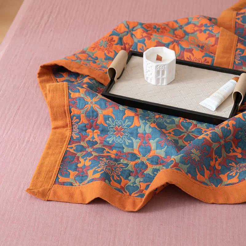 Buntes Tischset mit floralem Muster, orange-blau, dekorativ, Baumwolle, auf rosa Tischdecke.