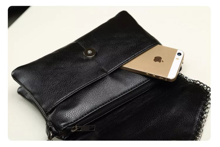 Schwarze Ledertasche mit Kettengurt, enthält ein goldenes Smartphone, stilvoll und elegant.