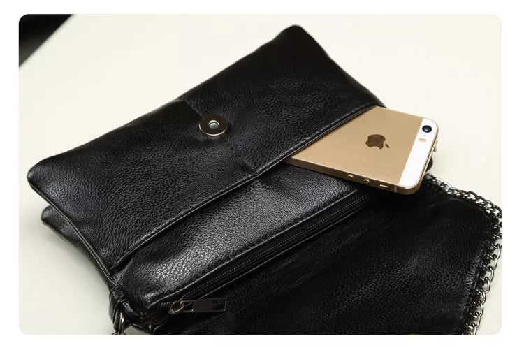 Schwarze Ledertasche mit Kettengurt, enthält ein goldenes Smartphone, stilvoll und elegant.