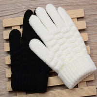 Schwarze und weiße Strickhandschuhe auf Holzunterlage, Wintermode Accessoires.