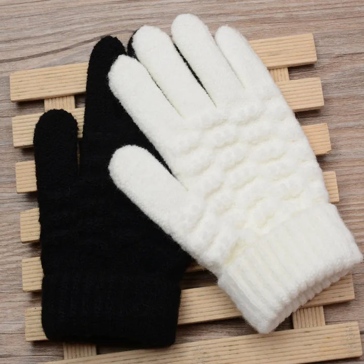 Schwarze und weiße Strickhandschuhe auf Holzunterlage, Wintermode Accessoires.