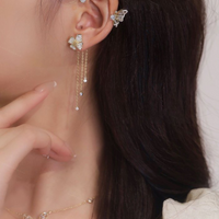 Frau mit goldenen Schmetterling-Ohrringen, funkelnde Ketten, eleganter Schmuck, Nahaufnahme.