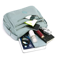 Hellblaue Umhängetasche mit Reißverschlüssen, gefüllt mit Alltagsgegenständen, ideal für Reisen.