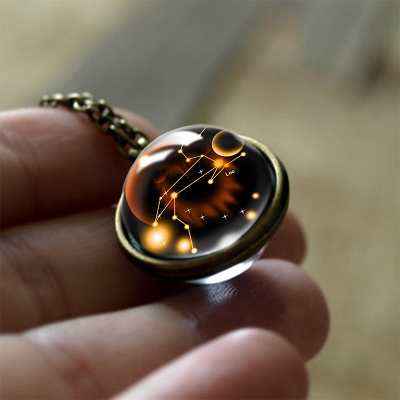 Hand hält bronzenen Löwe-Sternzeichen-Anhänger mit Glaskuppel, astrologisches Schmuckstück.