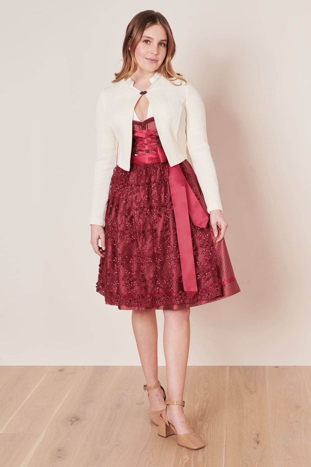 Frau in rotem Spitzenkleid mit weißer Strickjacke, elegantes Outfit, Mode für besondere Anlässe.