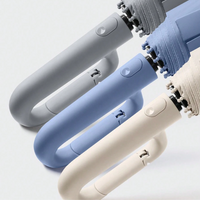 Graue, blaue und beige Regenschirme mit ergonomischem Griff, kompakt und faltbar.