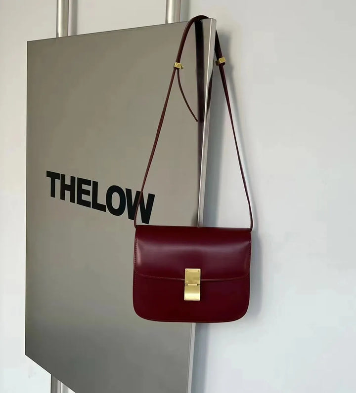 Bordeauxrote Ledertasche mit goldener Schnalle, Umhängetasche, elegantes Design, Damenmode.