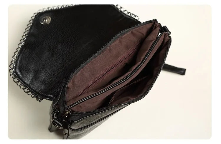 Schwarze Lederhandtasche mit Kettenriemen, geöffnet, braunes Innenfutter, modisch, elegant.
