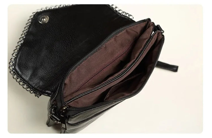 Schwarze Lederhandtasche mit Kettenriemen, geöffnet, braunes Innenfutter, modisch, elegant.
