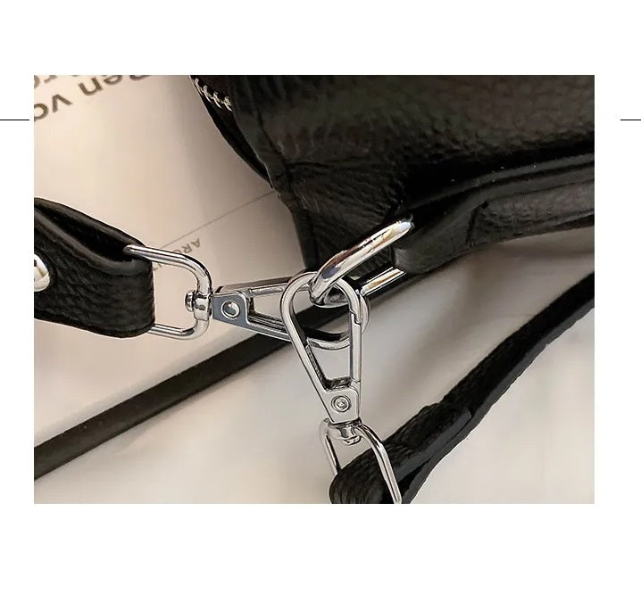 Schwarze Ledertasche mit silbernem Karabinerhaken, Nahaufnahme, modisches Accessoire.