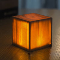 Leuchtender Holzwürfel auf Tisch, warmes Licht, dekorative Lampe, modernes Design, Innenbeleuchtung.