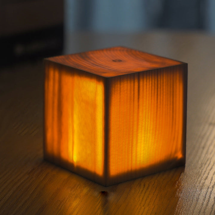 Leuchtender Holzwürfel auf Tisch, warmes Licht, dekorative Lampe, modernes Design, Innenbeleuchtung.