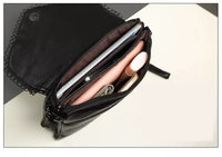 Schwarze Ledertasche mit Reißverschluss, gefüllt mit Kosmetik und Smartphone auf weißem Hintergrund.