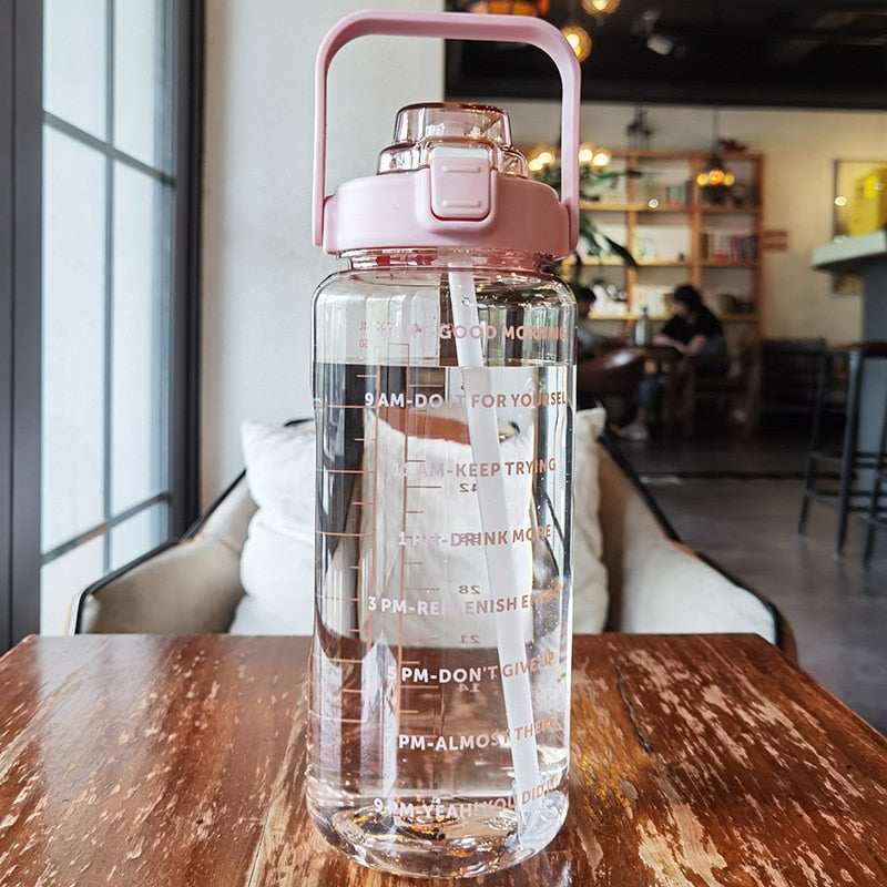 Klarglas-Wasserflasche mit rosa Deckel, Motivationsmarkierungen, 2 Liter, auf Holztisch.
