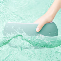 Hand hält grünes, wasserdichtes Kissen im Wasser, ergonomisch, für Komfort und Entspannung.