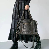 Frau mit schwarzer Ledertasche, gehäkeltem Rock und Stiefeln, modisch, elegant, Accessoire.
