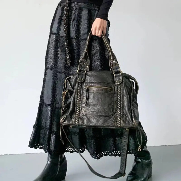 Frau mit schwarzer Ledertasche, gehäkeltem Rock und Stiefeln, modisch, elegant, Accessoire.