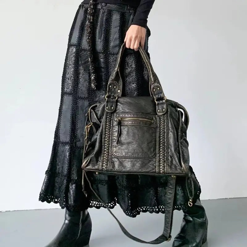 Frau mit schwarzer Ledertasche, gehäkeltem Rock und Stiefeln, modisch, elegant, Accessoire.