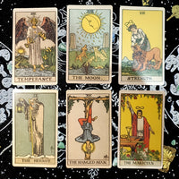 Sechs Tarotkarten auf schwarzem Tuch: Temperance, The Moon, Strength, The Hermit, The Hanged Man, The Magician.
