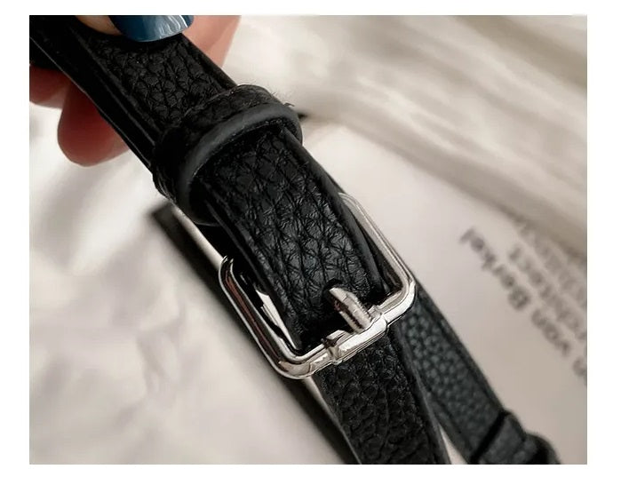 Schwarzer Ledergürtel mit silberner Schnalle, Nahaufnahme, modisches Accessoire, Damenmode.