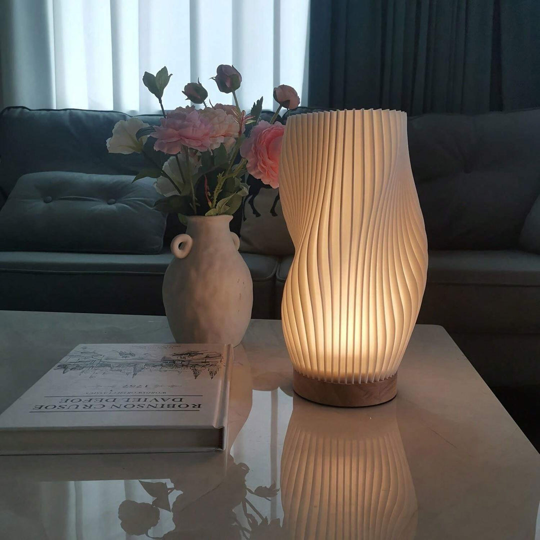 Moderne Tischlampe aus Holz und Papier, beleuchtet, neben Vase mit Blumen auf Couchtisch.