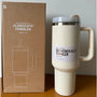 Beiger Flowstate Quencher H2.0 Tumbler, 40 oz, mit Griff, neben Verpackung, ideal für Hydration.