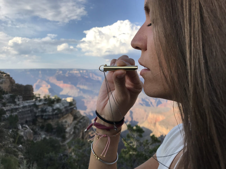 Frau mit Stressabbau-Halskette in der Natur, Atemtherapie, Entspannung, Metallanhänger.