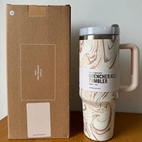 Beiger Stanley Quencher H2.0 Tumbler, 1,2L, mit Marmormuster, neben Verpackung.