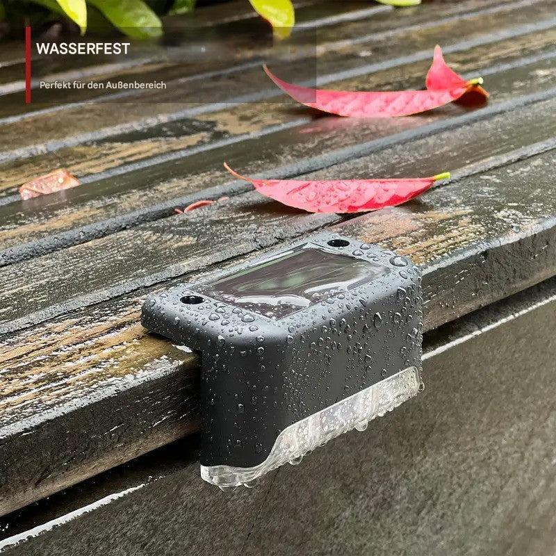 Wasserdichte LED-Solarleuchte für Außenbereich, schwarz, auf Holzoberfläche mit Regentropfen.