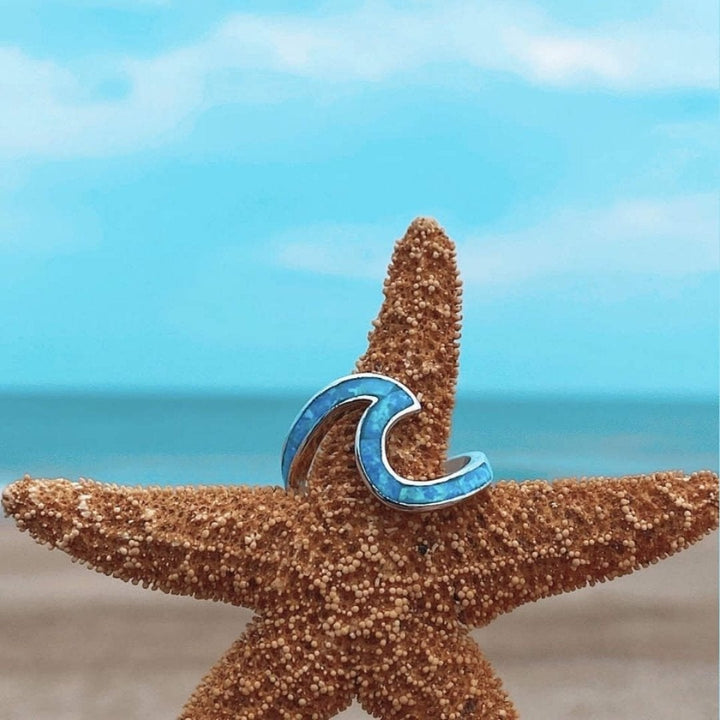 Blauer Wellenring auf Seestern am Strand, maritimer Schmuck, Sommeraccessoire, Ozean-Thema.