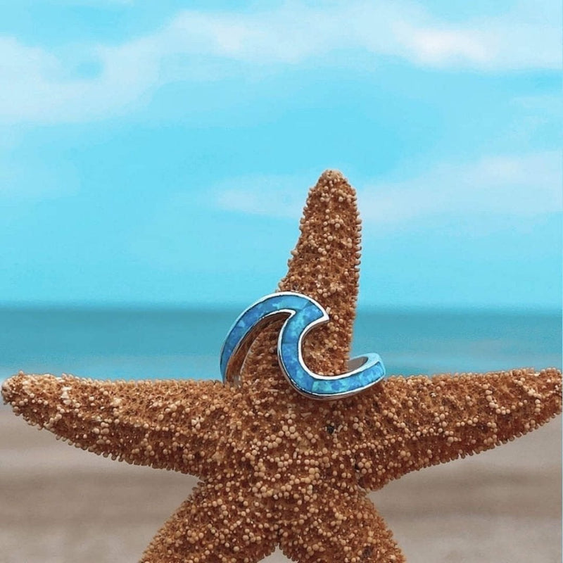Blauer Wellenring auf Seestern am Strand, maritimer Schmuck, Sommeraccessoire, Ozean-Thema.