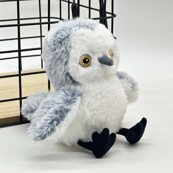 Kuscheltier Schneeeule, grau-weiß, Plüsch, sitzend vor Metallkäfig, Kinderzimmer-Dekoration.