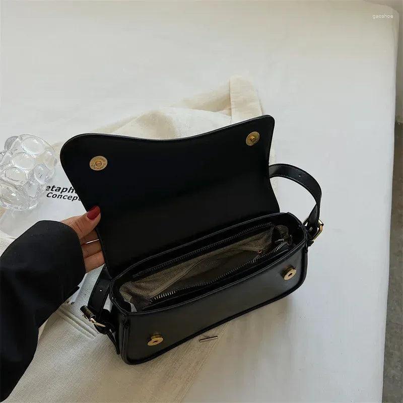 Schwarze Lederhandtasche mit offenem Reißverschluss auf weißem Hintergrund, elegantes Design.