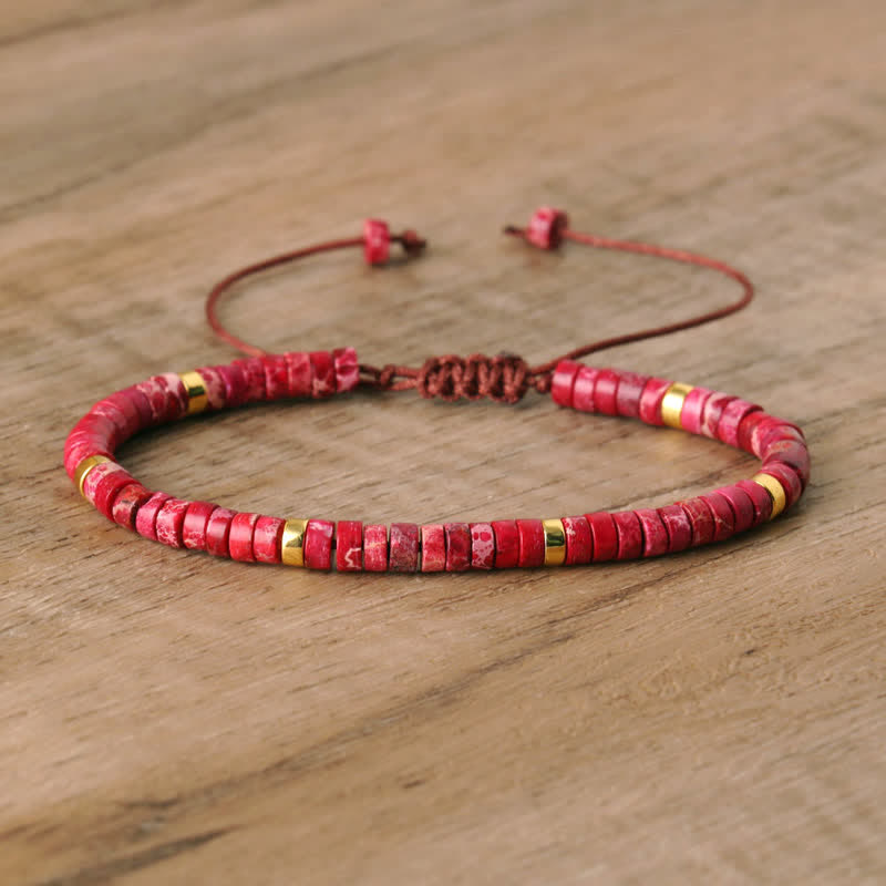 Rotes Perlenarmband aus Stein mit gelben Akzenten auf Holzoberfläche, verstellbar.