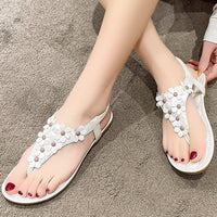 Weiße Damen-Sandalen mit Blumenmuster, flach, bequem, Sommermode, auf Teppich.