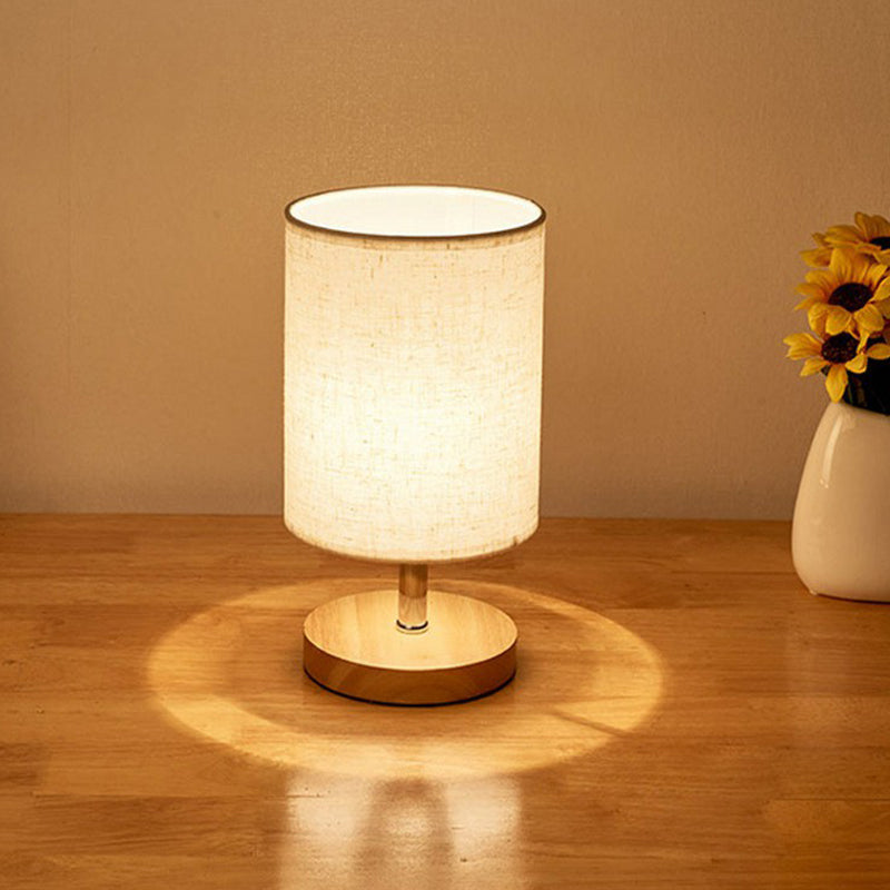 Beige Tischlampe mit Stoffschirm auf Holztisch, moderne Beleuchtung, Inneneinrichtung.