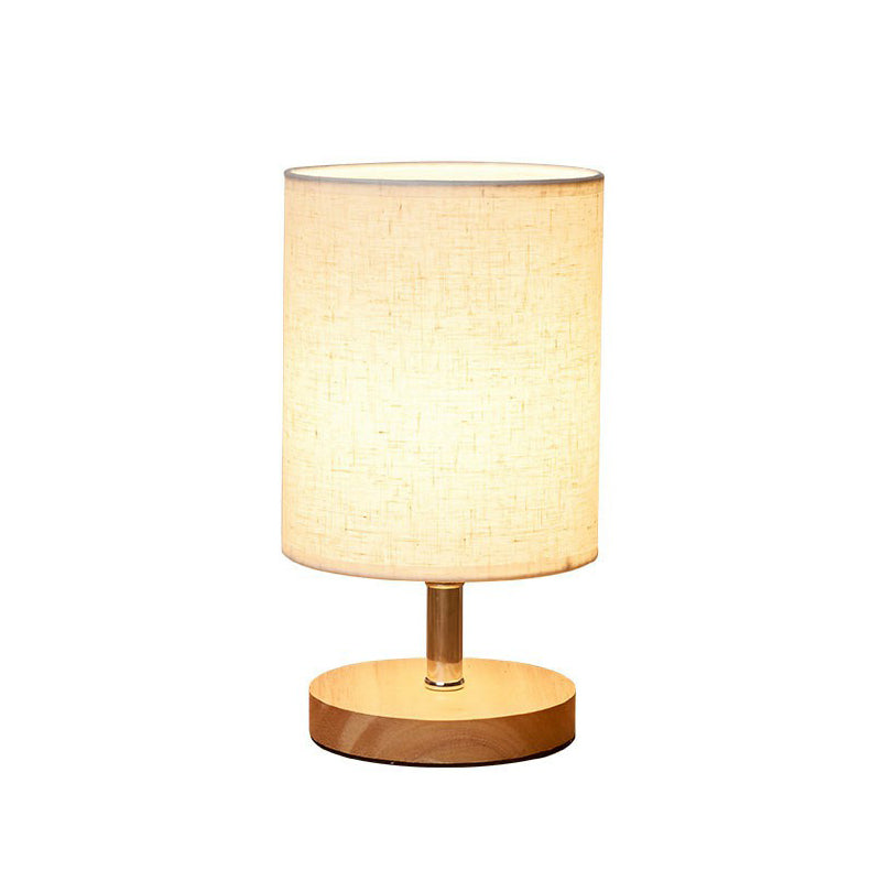 Beige Tischlampe mit Holzfuß, zylindrischer Stoffschirm, moderne Beleuchtung, Inneneinrichtung.