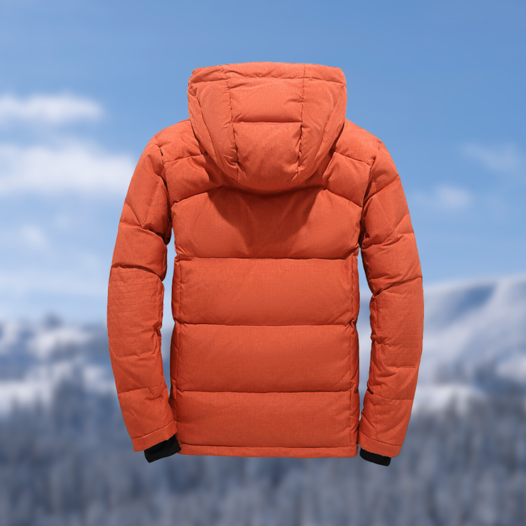 Orangefarbene Daunenjacke mit Kapuze, Winterbekleidung, isoliert, vor verschneiter Berglandschaft.
