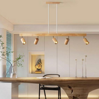 Moderne Holz-Pendelleuchte mit fünf verstellbaren Spots über Esstisch im minimalistischen Raum.