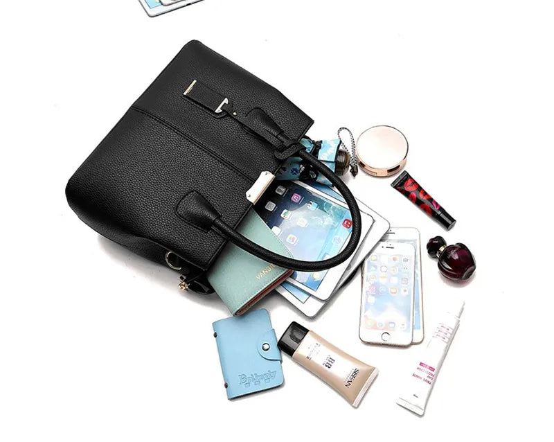 Schwarze Lederhandtasche mit Smartphone, Kosmetik und Notizbuch auf weißem Hintergrund.