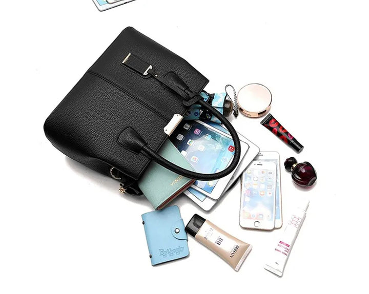 Schwarze Lederhandtasche mit Smartphone, Kosmetik und Notizbuch auf weißem Hintergrund.