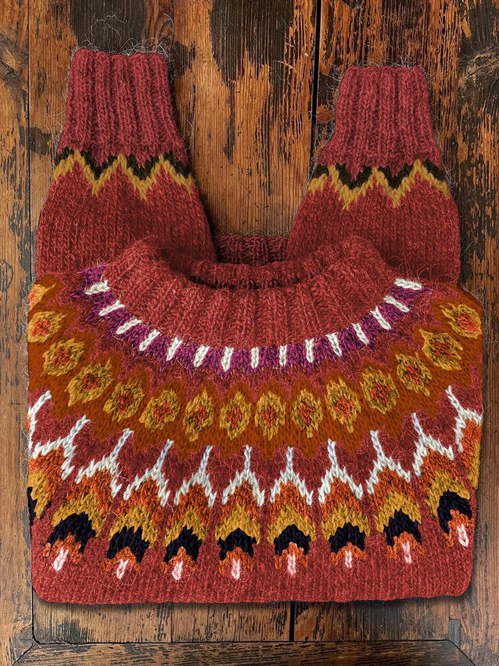 Roter Norwegerpullover aus Wolle mit buntem Strickmuster auf rustikalem Holztisch.