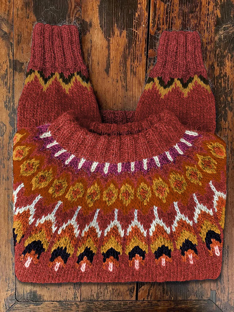 Roter Norwegerpullover aus Wolle mit buntem Strickmuster auf rustikalem Holztisch.